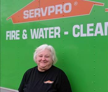 Female employee Bobbie standing in front of green SERVPRO vehicle