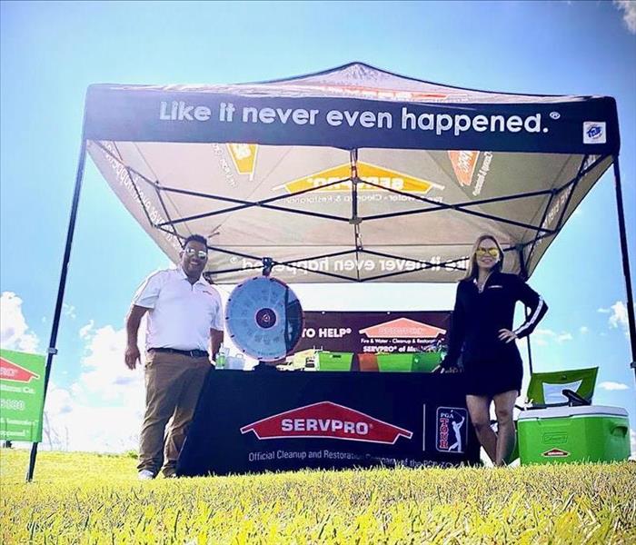 Marketing reps standing in front of SERVPRO tent at golf outing