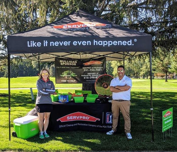 Marketing reps standing in front of SERVPRO tent at golf outing