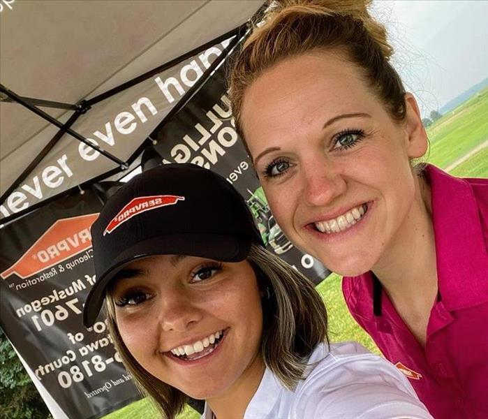 Two Female SERVPRO Marketing employees standing in front of banner 
