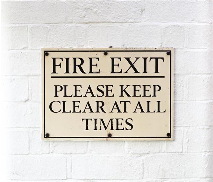 Fire Exit Sign hanging on white brick wall