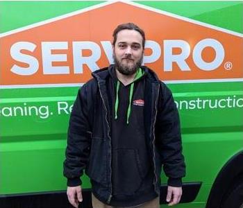 Male employee, Liam, standing in front of green SERVPRO van