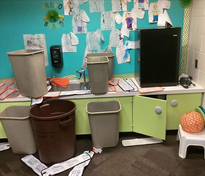 Classroom with water damage, trash cans catching water from ceiling